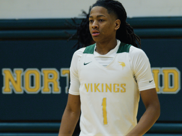Young male athlete wearing a white jersey with green writing